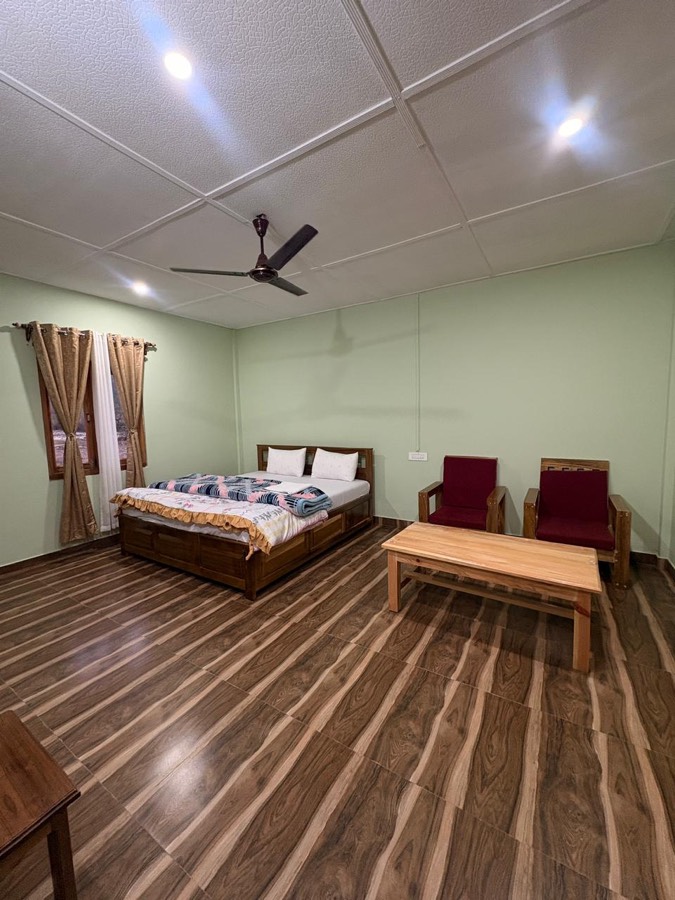 Spacious cottage room with bed and sitting area at Phuntso River Cottages