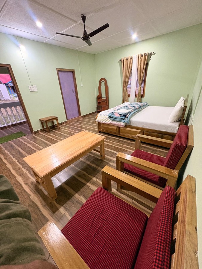 Neat cottage room with seating and balcony access at Phuntso River Cottages